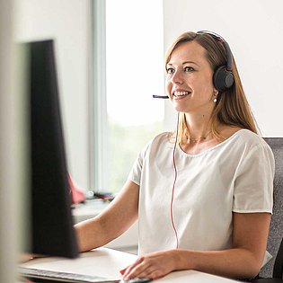 Eine Frau mit Headset sitzt vor einem Computer